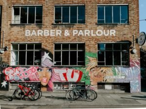 An urban scene of a barber shop with colorful graffiti art and parked bicycles in London.